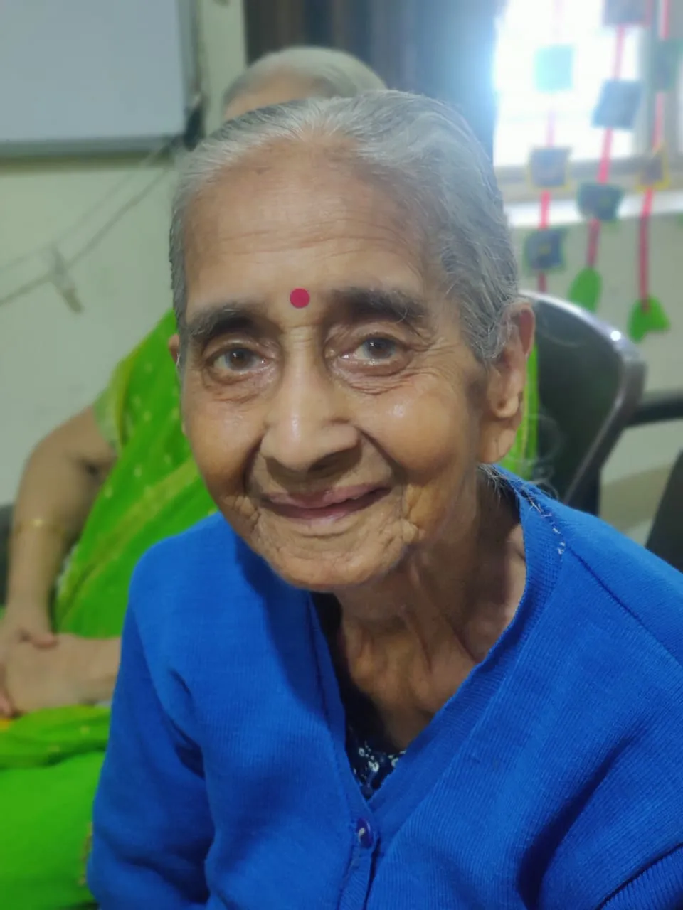 Smiling senior citizen proudly holding a craft item